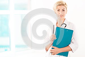 Young doctor in white coat with green tablet