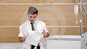 Young doctor in white robe checks a perfusion while the second one is entering the frame with a clipboard in hands