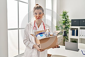 Young doctor woman holding box with medical items depressed and worry for distress, crying angry and afraid