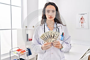 Young doctor woman holding money depressed and worry for distress, crying angry and afraid