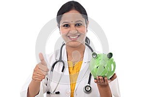 Young doctor woman holding a piggy bank