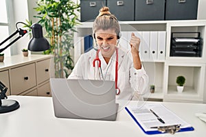Young doctor woman wearing doctor uniform working using computer laptop annoyed and frustrated shouting with anger, yelling crazy