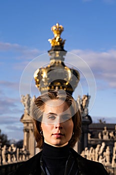 Young domineering imperious short-haired blond woman with golden crown on head