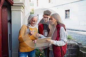 Young door to door volunteers talking to senior woman and taking survey at her front door.