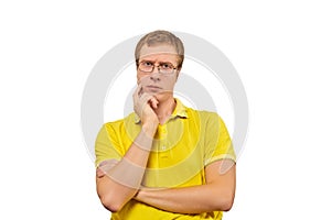 Young doubting man in glasses, man in yellow T-shirt isolated on white background