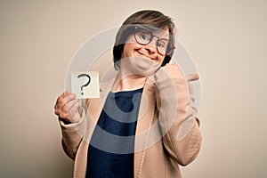 Young down syndrome business woman holding question mark paper as doubt symbol very happy pointing with hand and finger to the