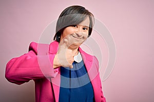 Young down syndrome business woman over pink background doing happy thumbs up gesture with hand