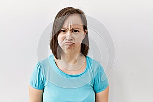 Young down syndrome woman standing over isolated background depressed and worry for distress, crying angry and afraid