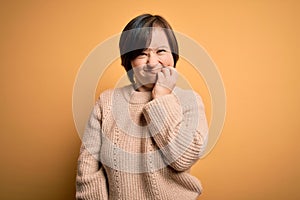 Young down syndrome woman wearing casual sweater over yellow background touching mouth with hand with painful expression because