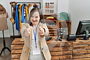 Young down syndrome woman working as manager at retail boutique pointing fingers to camera with happy and funny face