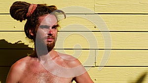 Young dreadful man on a yellow background topless
