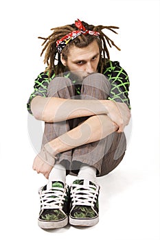 Young dreadlock man sits isolated photo