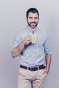 Young dreaming brunet bearded worker in formal wear is standing