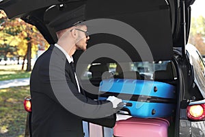 Young driver loading suitcases into car trunk
