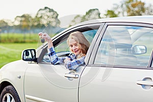 Young driver looking out of the car window holding a key