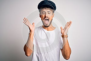 Young driver man with beard wearing hat standing over isolated white background celebrating mad and crazy for success with arms