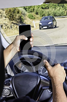 Young driver, using smartphone, on the road in the car