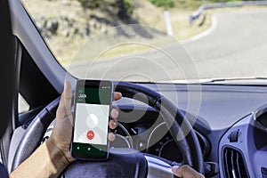 Young driver, using smartphone, on the road in the car