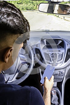 Young driver, using smartphone, on the road in the car