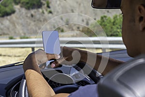 Young driver, using smartphone, on the road in the car