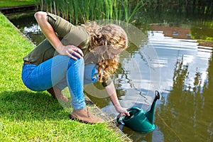 Young dutch woman filling green caster with water