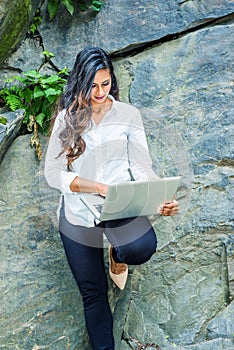 Young East Indian American Woman with long hair working on laptop computer outdoor in New York