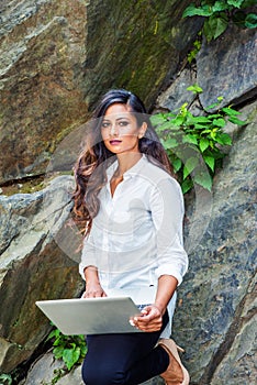 Young East Indian American Woman with long hair working on laptop computer outdoor in New York