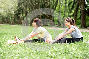 Young and elder woman doing yoga in the park