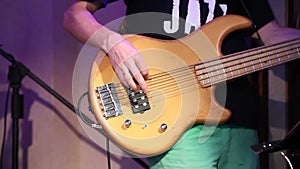 Young electric guitarist player playing bass guitar, closeup