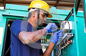 young electrical engineer with protective workware repairing or connecting wires by using screw driver at workplace -