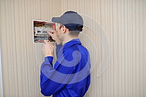 Young electrician in blue overall disassembling a electrical panel with fuses in a house