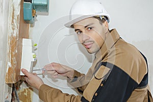 Young electrician builder engineer installing fuse box