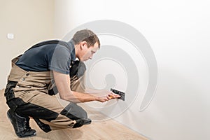 A young electrician installing an electrical socket in a new house.