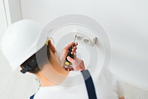 A young electrician installing an electrical socket in a new house