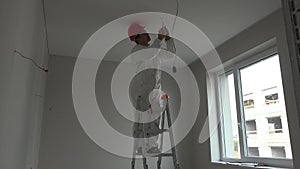Young electrician installing smoke detector fire alarm on ceiling