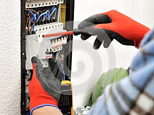 Young electrician technician at work on a electrical panel with