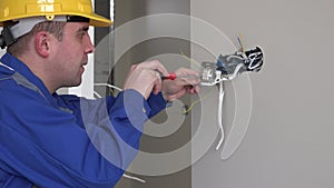 Young electrician at work with wall outlet and screwdriver installing sockets