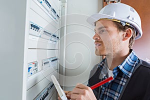 Young electrician working on electric panel