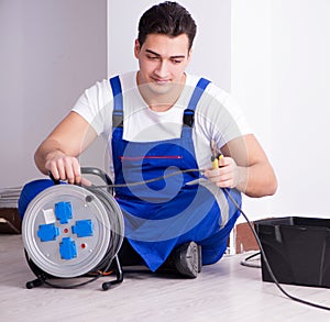 Young electrician working on socket at home