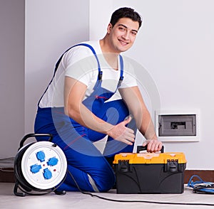 Young electrician working on socket at home