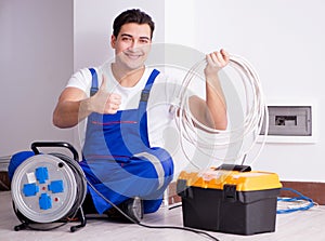 Young electrician working on socket at home