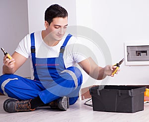 Young electrician working on socket at home