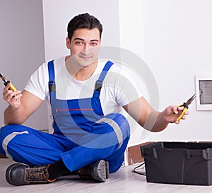 Young electrician working on socket at home