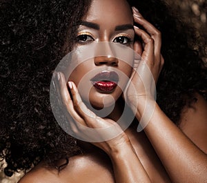 Young elegant african american woman with afro hair. Glamour makeup. Golden Background.