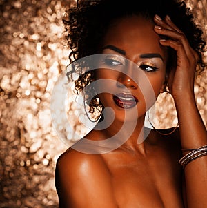 Young elegant african american woman with afro hair. Glamour makeup. Golden Background.