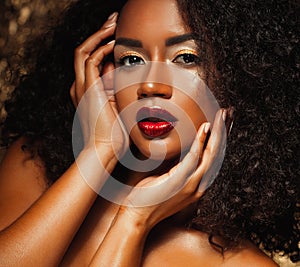 Young elegant african american woman with afro hair. Glamour makeup. Golden Background.