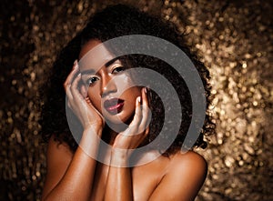 Young elegant african american woman with afro hair. Glamour makeup. Golden Background.