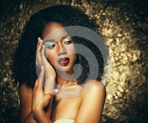 Young elegant african american woman with afro hair. Glamour makeup. Golden Background.