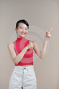 Young elegant beautiful Asian woman smiling and pointing to empty copy space isolated on white background