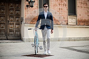 Young elegant businessman with bicycle on the street